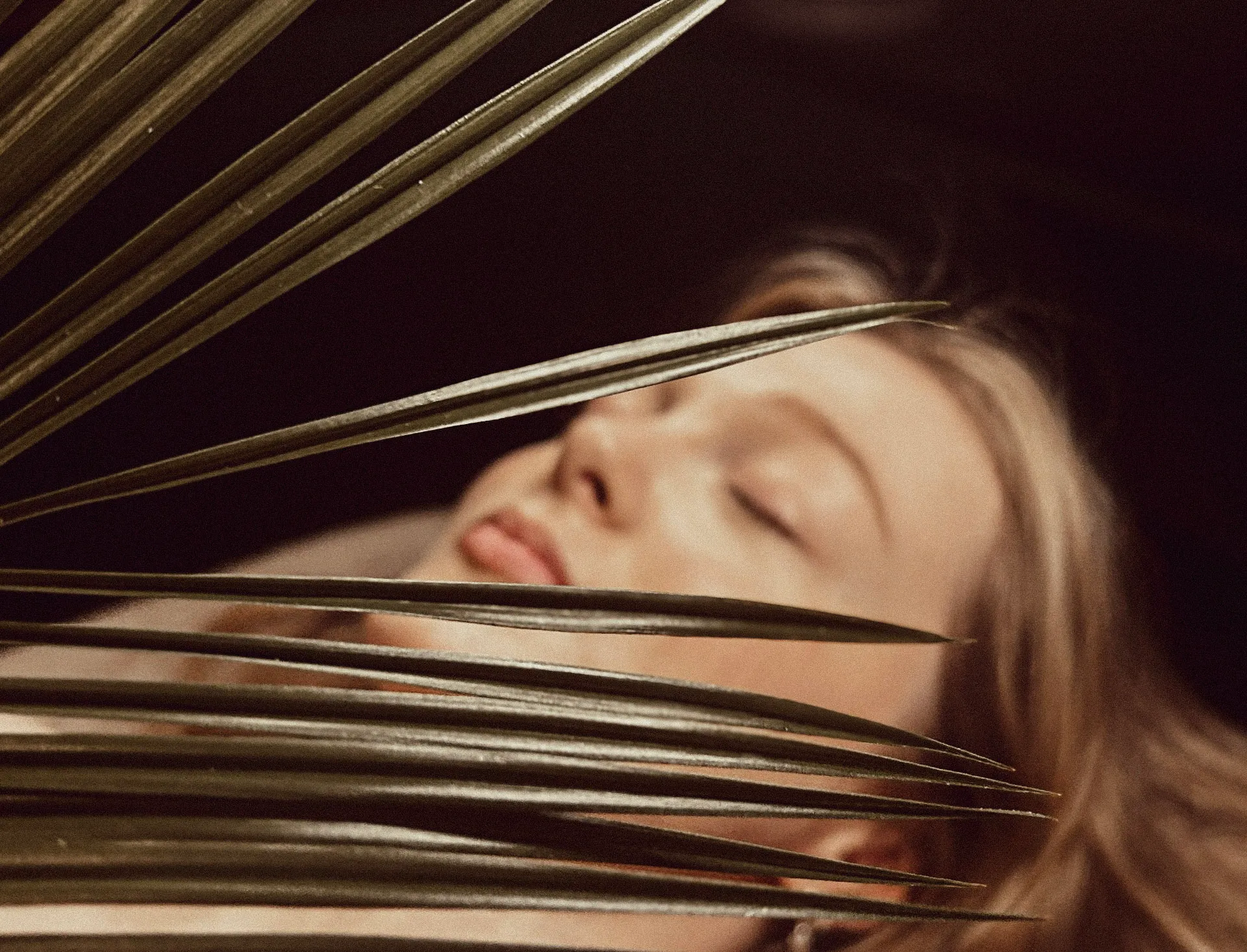 A client resting deeply with a palm leaf across her face, calm and fully at ease, at Artemis Therapies in Ruthin
